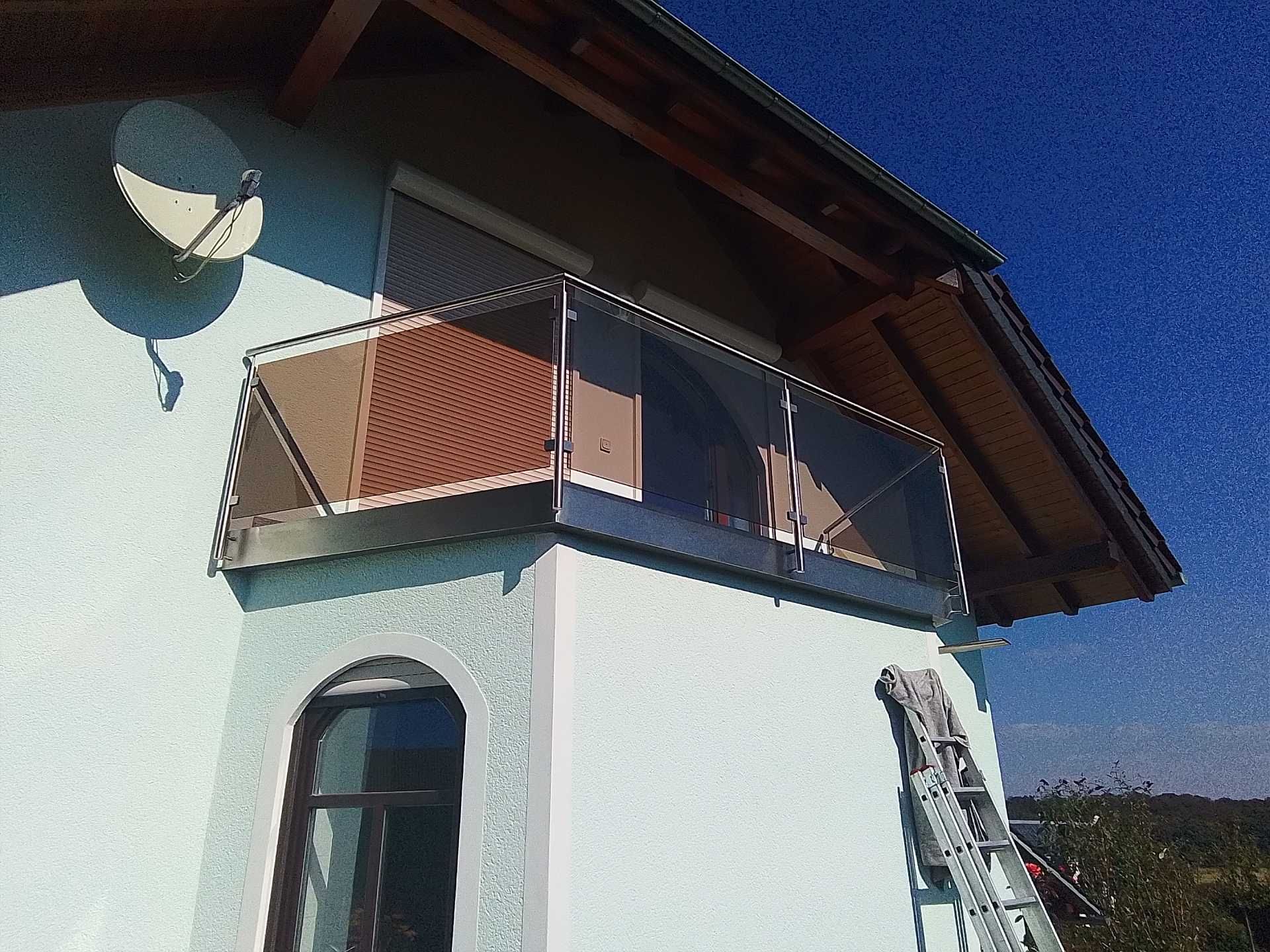 Balkon mit Metallgeländer und dekorativem Lochblech an Hausgiebel