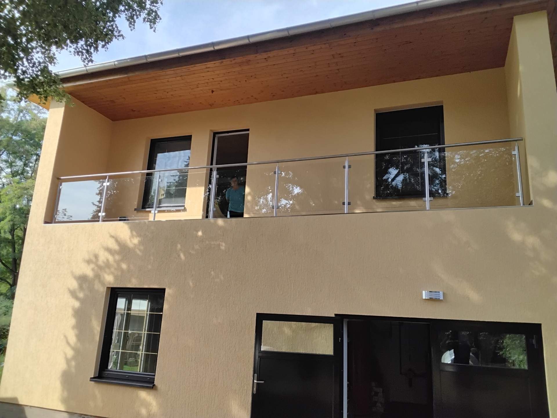 Balkon mit Glasgeländer an gelb gestrichener Hausfassade