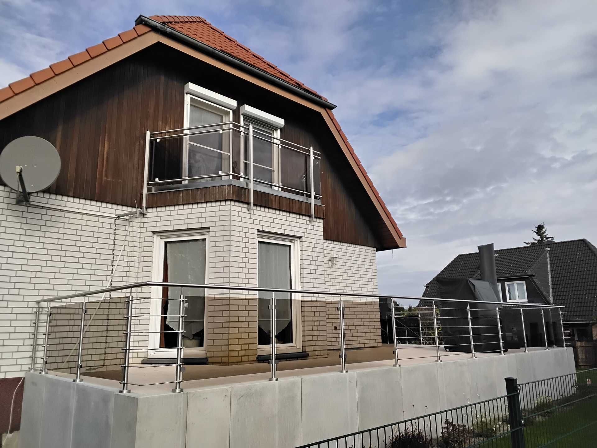 Zweigeschossiges Haus mit umlaufendem Edelstahl‑Glasbalkon