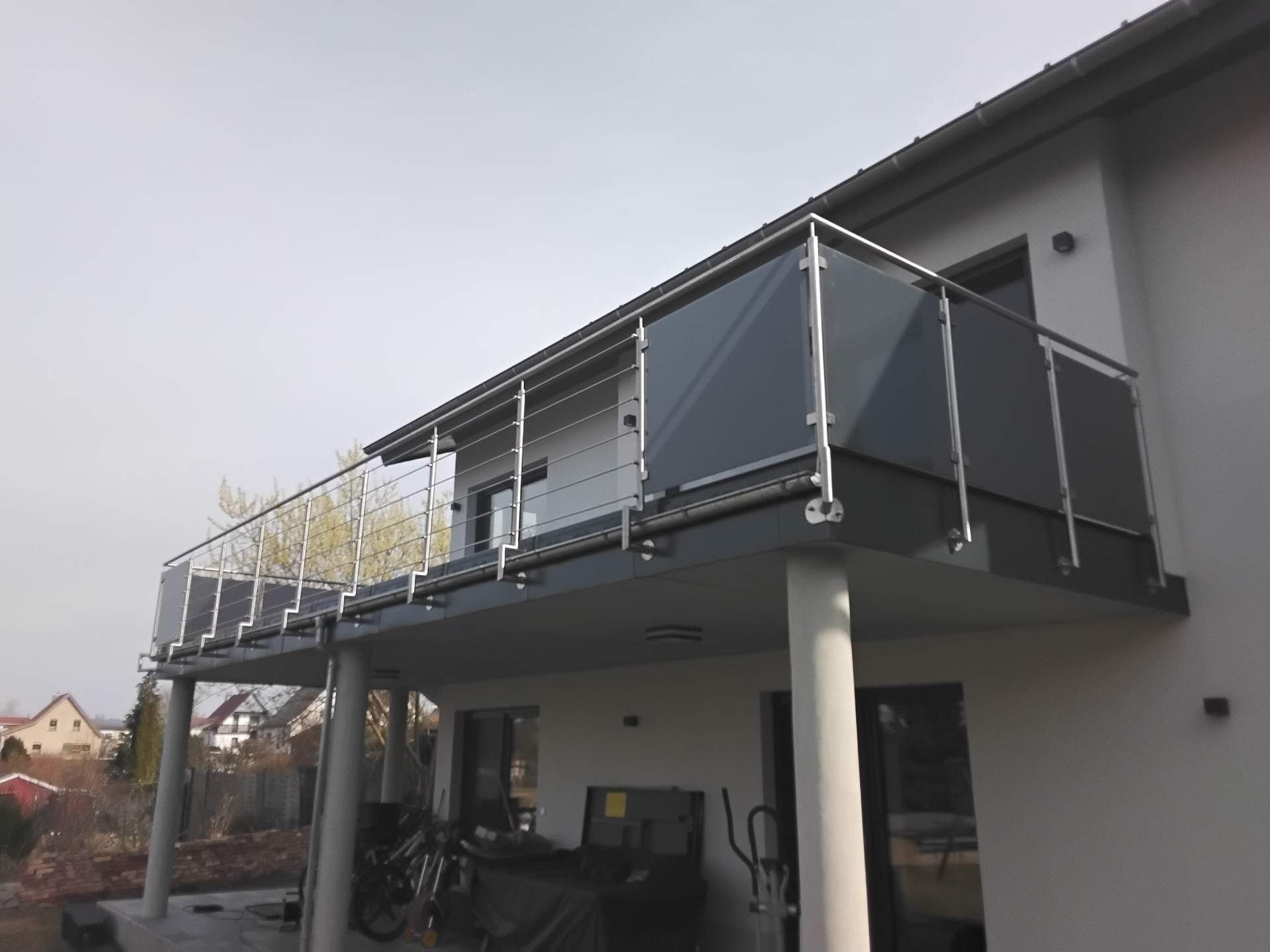Moderner Balkon mit dunklem Sichtschutz und Edelstahlpfosten an einem Wohnhaus
