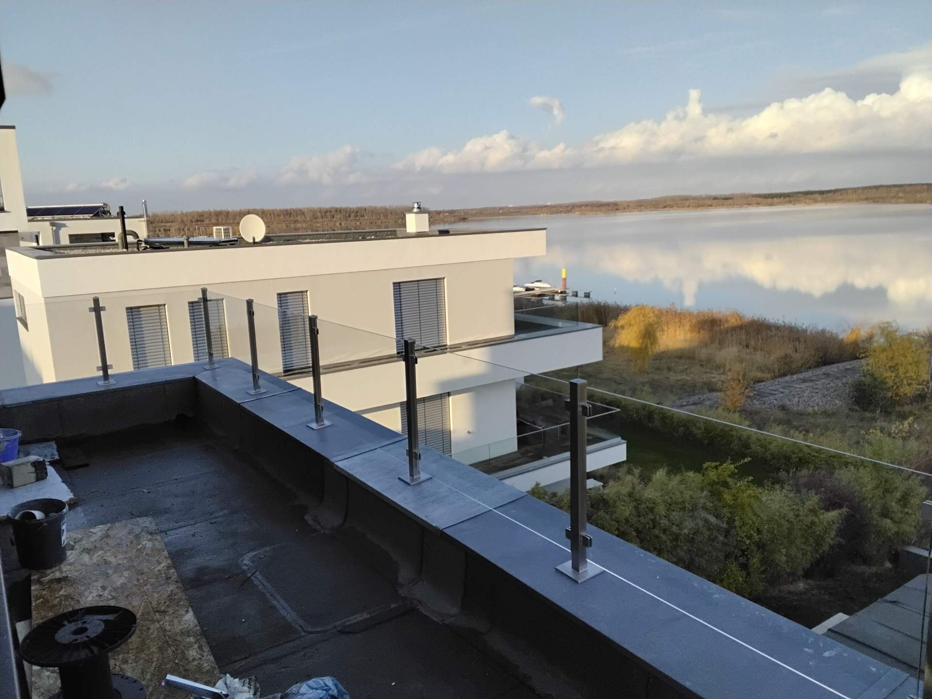 Flachdach-Balkon mit Glasgeländer und Blick auf eine Landschaft mit Wasser