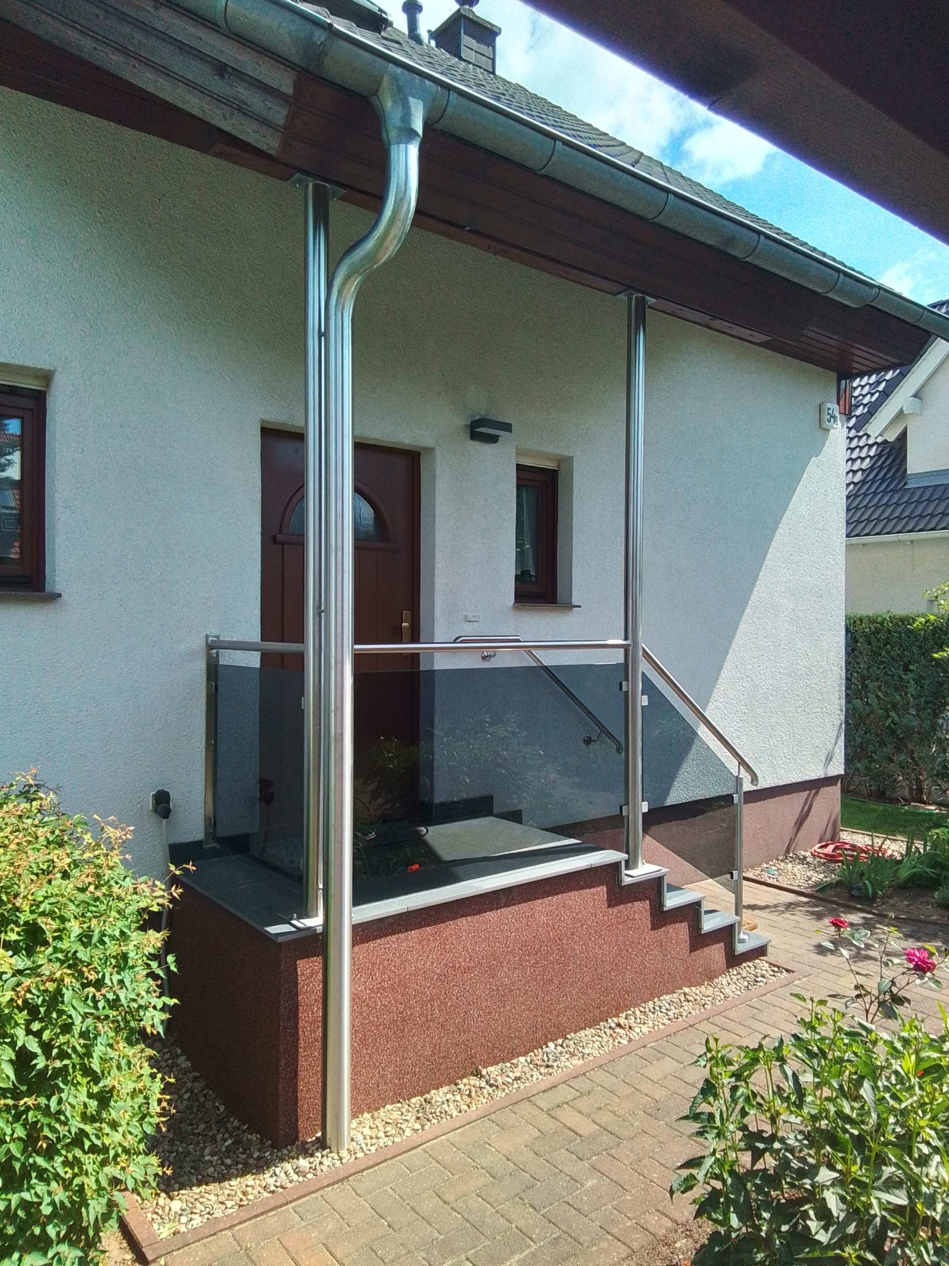 Überdachter Eingangsbereich mit Glasvordach und Edelstahlgeländer