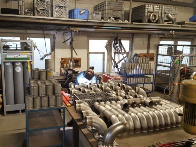 Werkstatt mit Edelstahlbauteilen und gelagerten Metallrohren im Arbeitsbereich