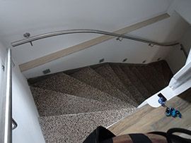 Geschwungene Treppe mit durchgehendem Edelstahlhandlauf im Treppenhaus