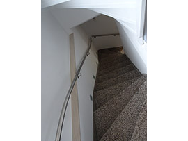 Schmale Wendeltreppe mit Edelstahlhandlauf in weißem Innenraum