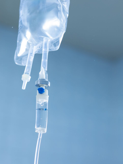 Une poche de perfusion et sa tubulure sur fond bleu clair.