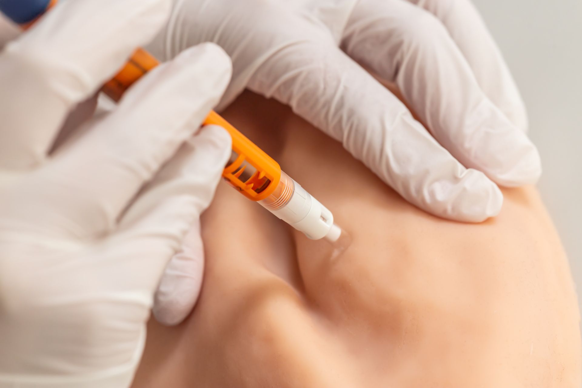 Un professionnel de santé avec des gants administre une injection dans l'épaule d'un patient à l'aide d'un stylo injecteur.