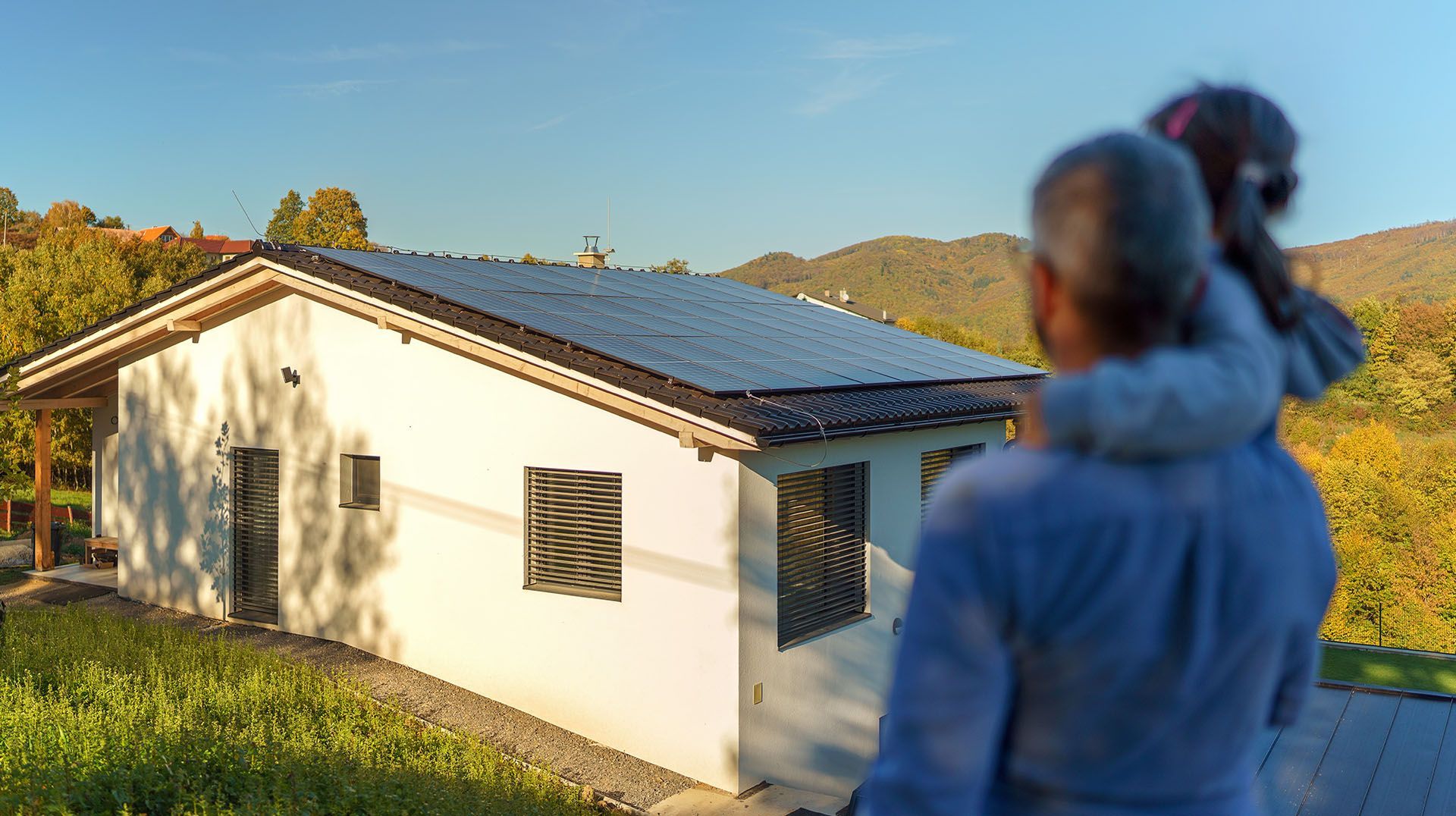 Père et sa fille regardant les panneaux solaires sur le toit de leur maison