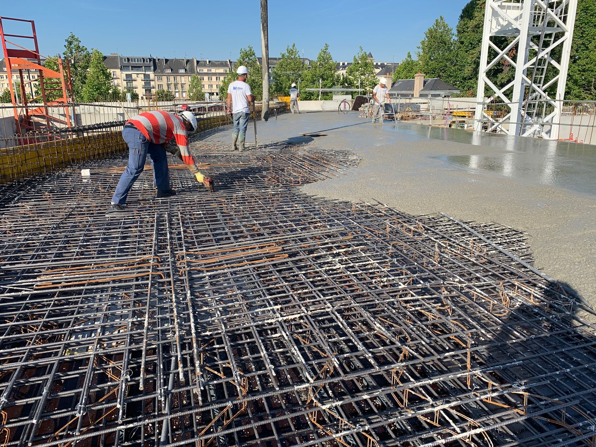 Professionnels sur un chantier extérieur où on coule du béton sur une armature en métal.
