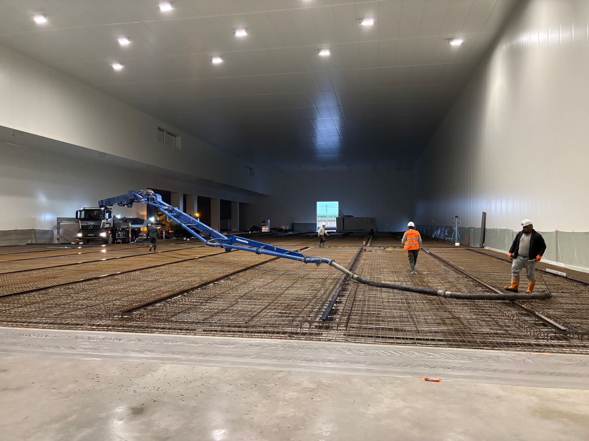 Bras articulé bleu fixé sur un camion utilisé pour couler une dalle de béton sur un chantier.