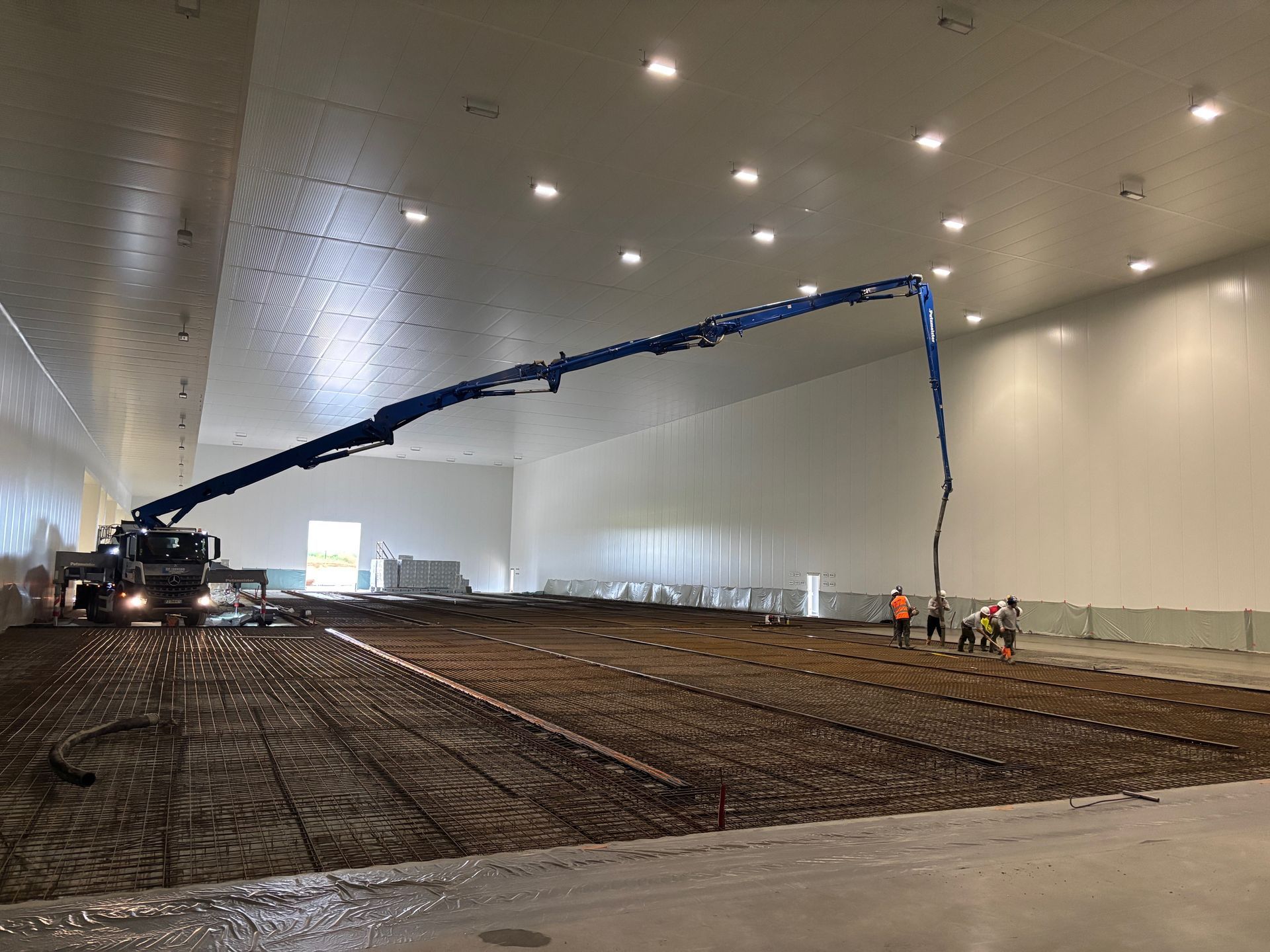 Coulage d'une dalle en béton dans un hangar industriel.