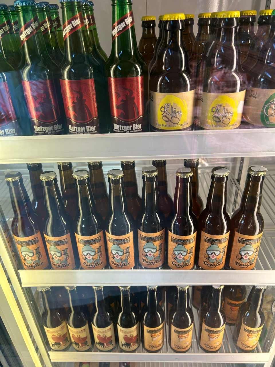 Un réfrigérateur rempli de bouteilles de bière de différentes étiquettes et couleurs.