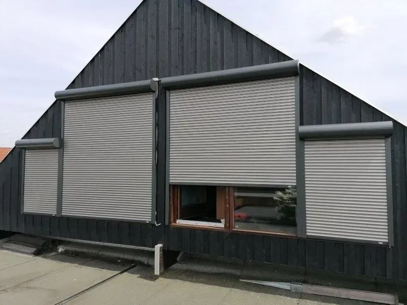 Dunkles Gebäude mit grauen Fensterläden.