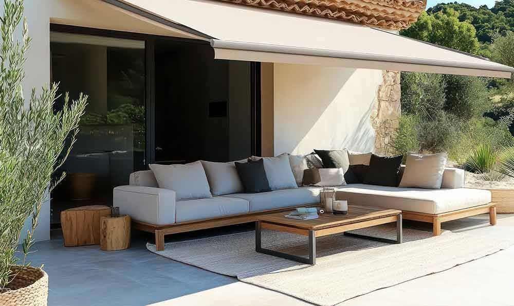 Terrasse mit hellbeigem Sofa, Couchtisch, Markise und Teppich.