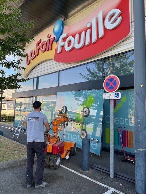 Un ouvrier utilise une nacelle pour installer une enseigne sur un magasin