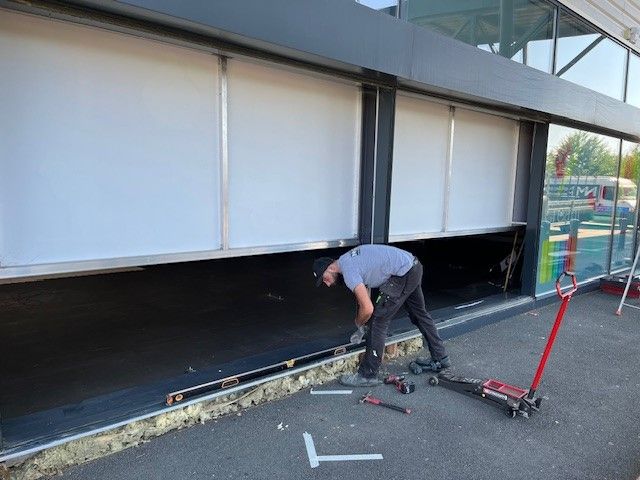Un ouvrier répare la porte d'un magasin