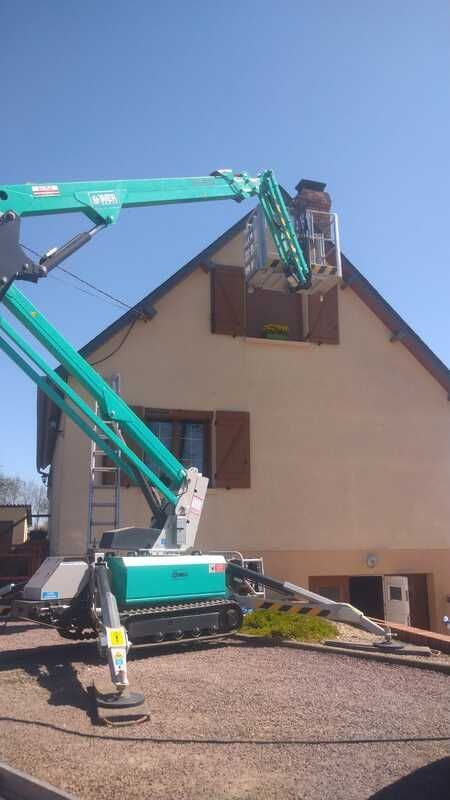 Un camion-nacelle travaille sur le toit d'une maison
