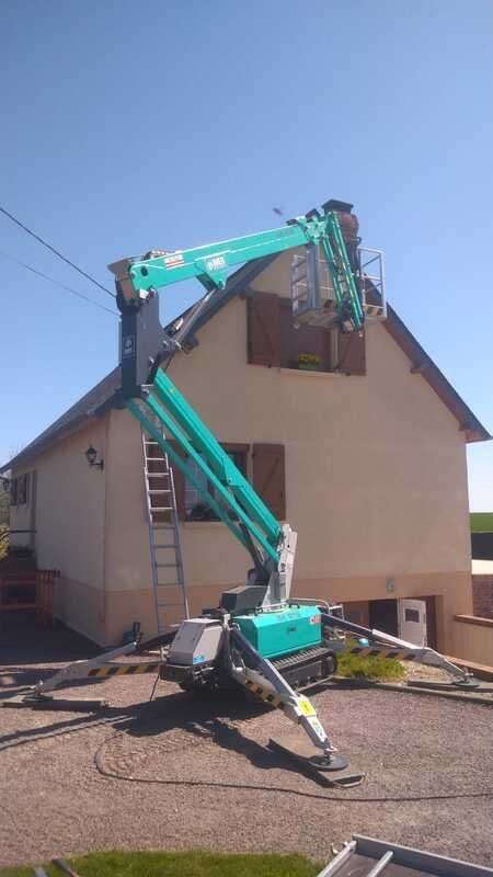 Une nacelle élévatrice travaille à l'extérieur d'une maison