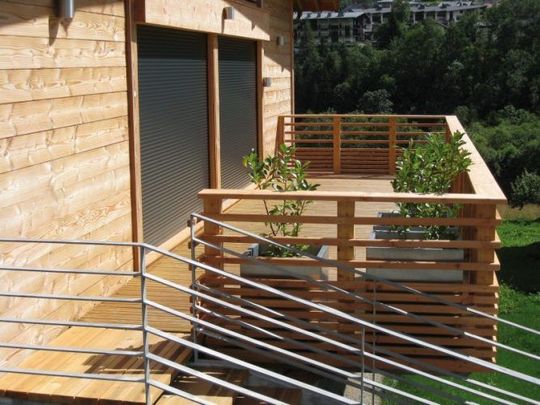 Terrasse en bois avec garde-corps, volet roulant et baie vitrée