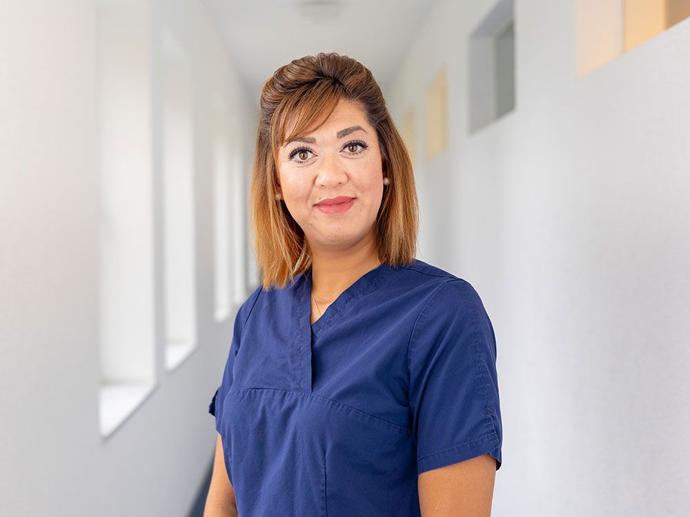 Eine Frau in einem blauen Kittel steht in einem Flur.