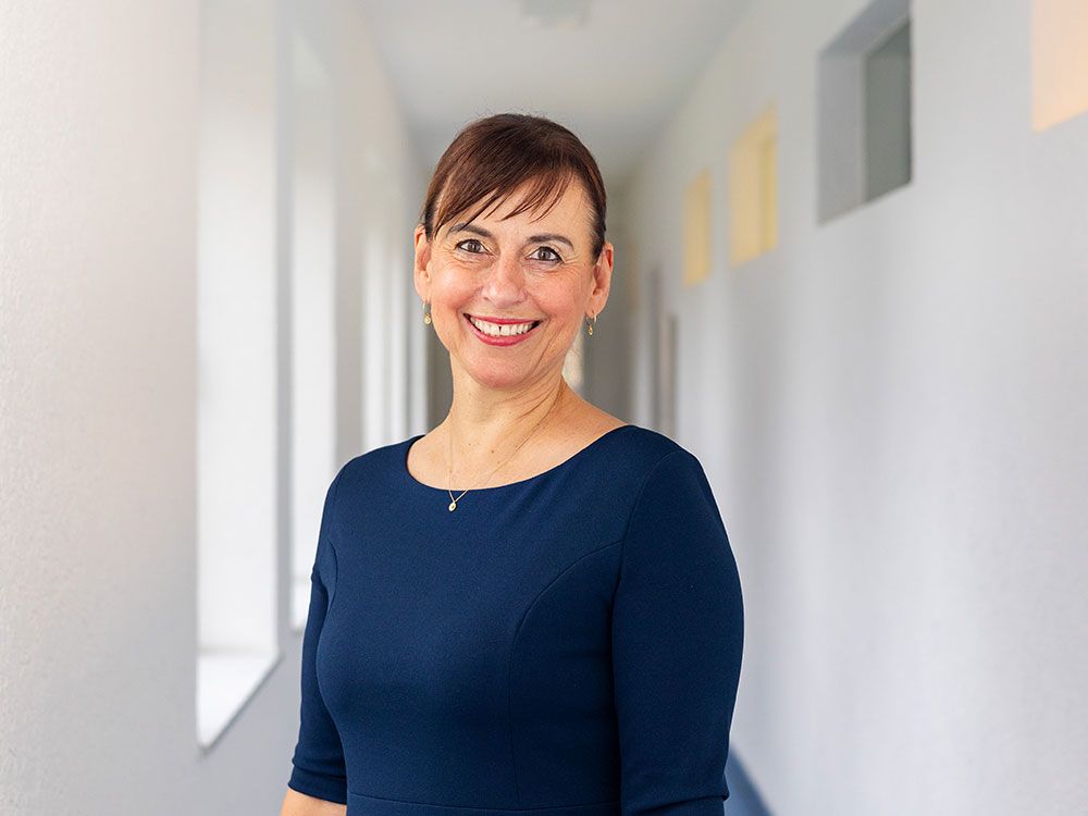 Eine Frau in einem blauen Kleid lächelt in einem Flur.