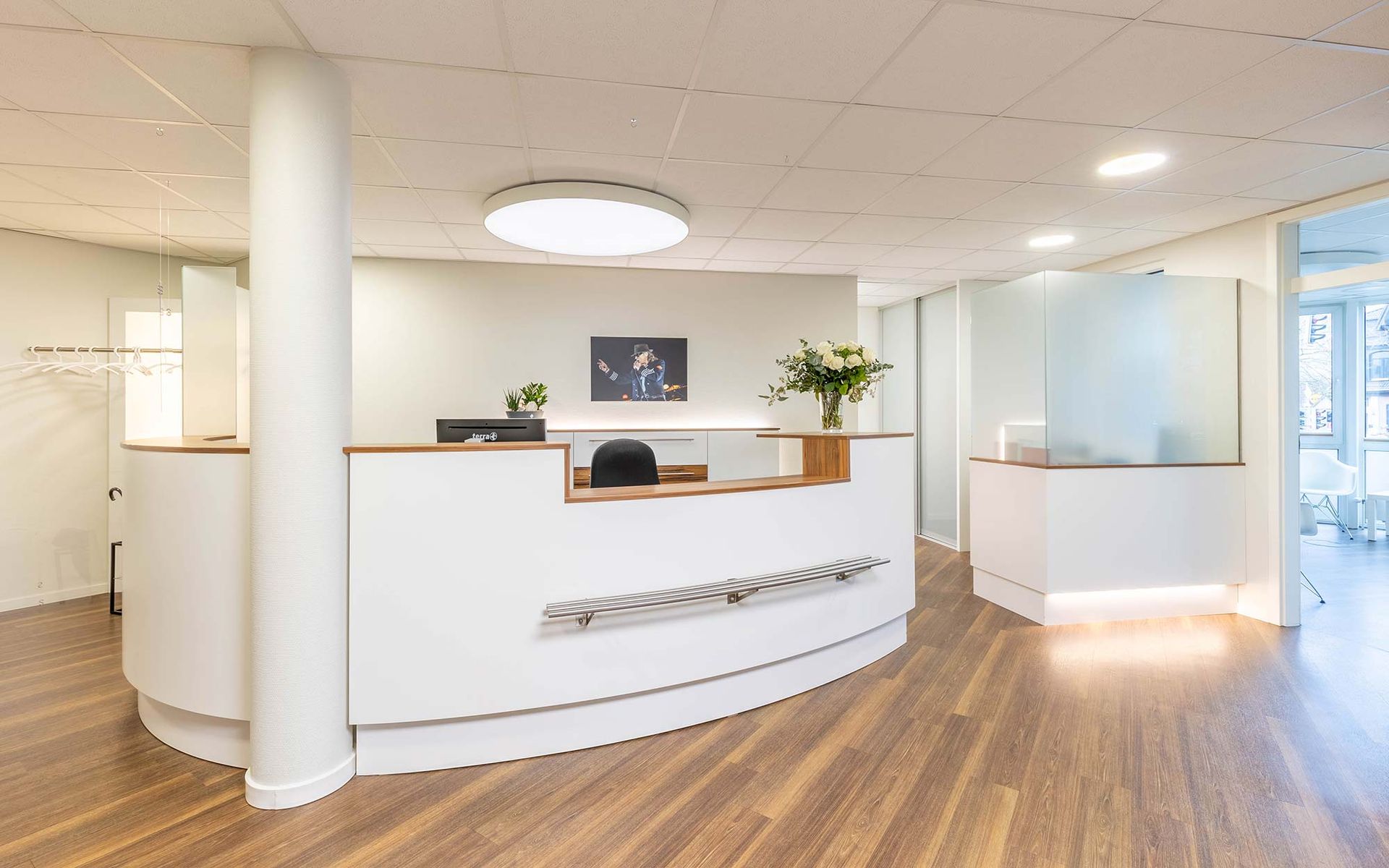 Ein Empfangsbereich in einem Krankenhaus mit einem weißen Tresen und Holzboden.