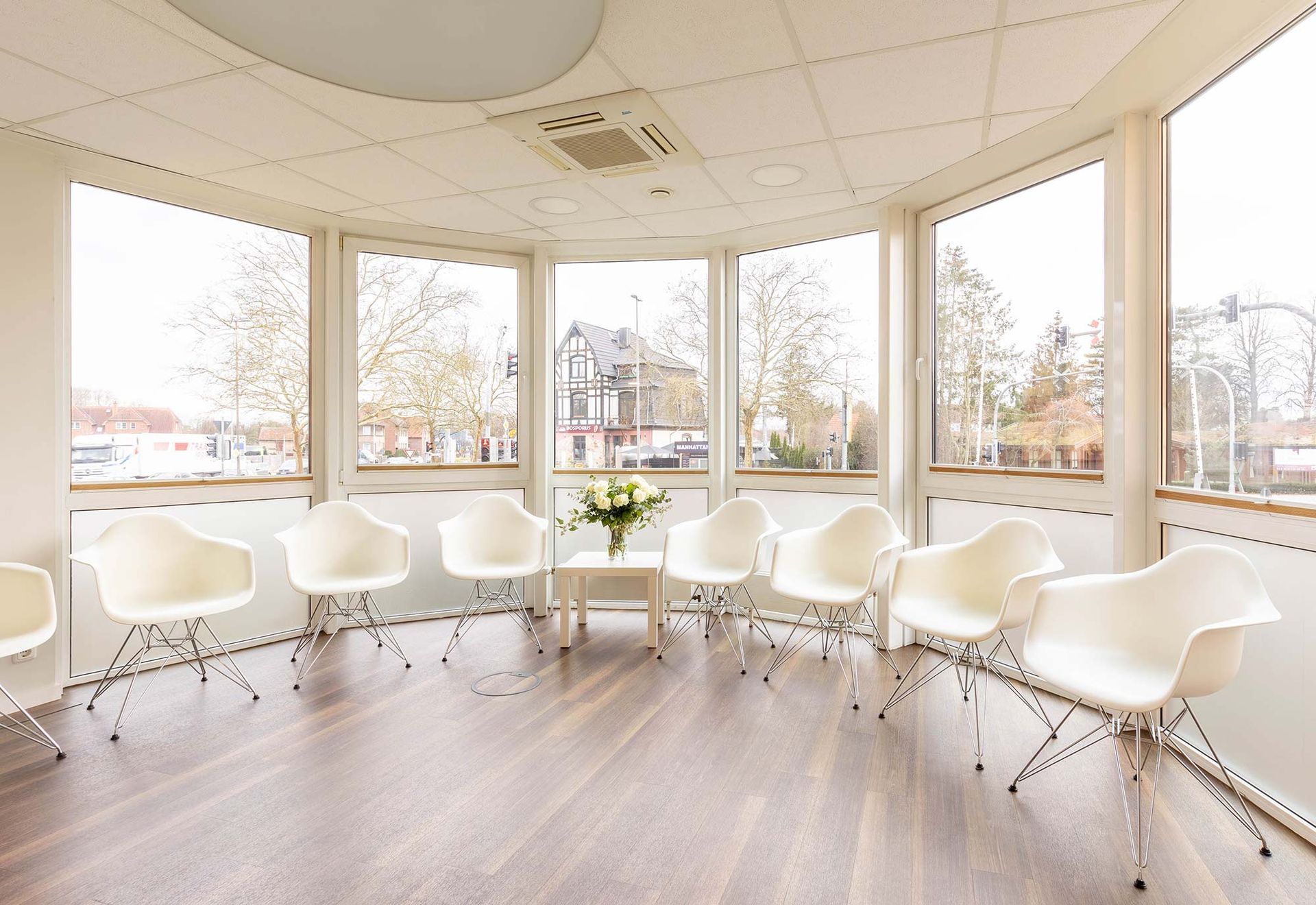 Ein Wartezimmer mit weißen Stühlen und einer Vase mit Blumen