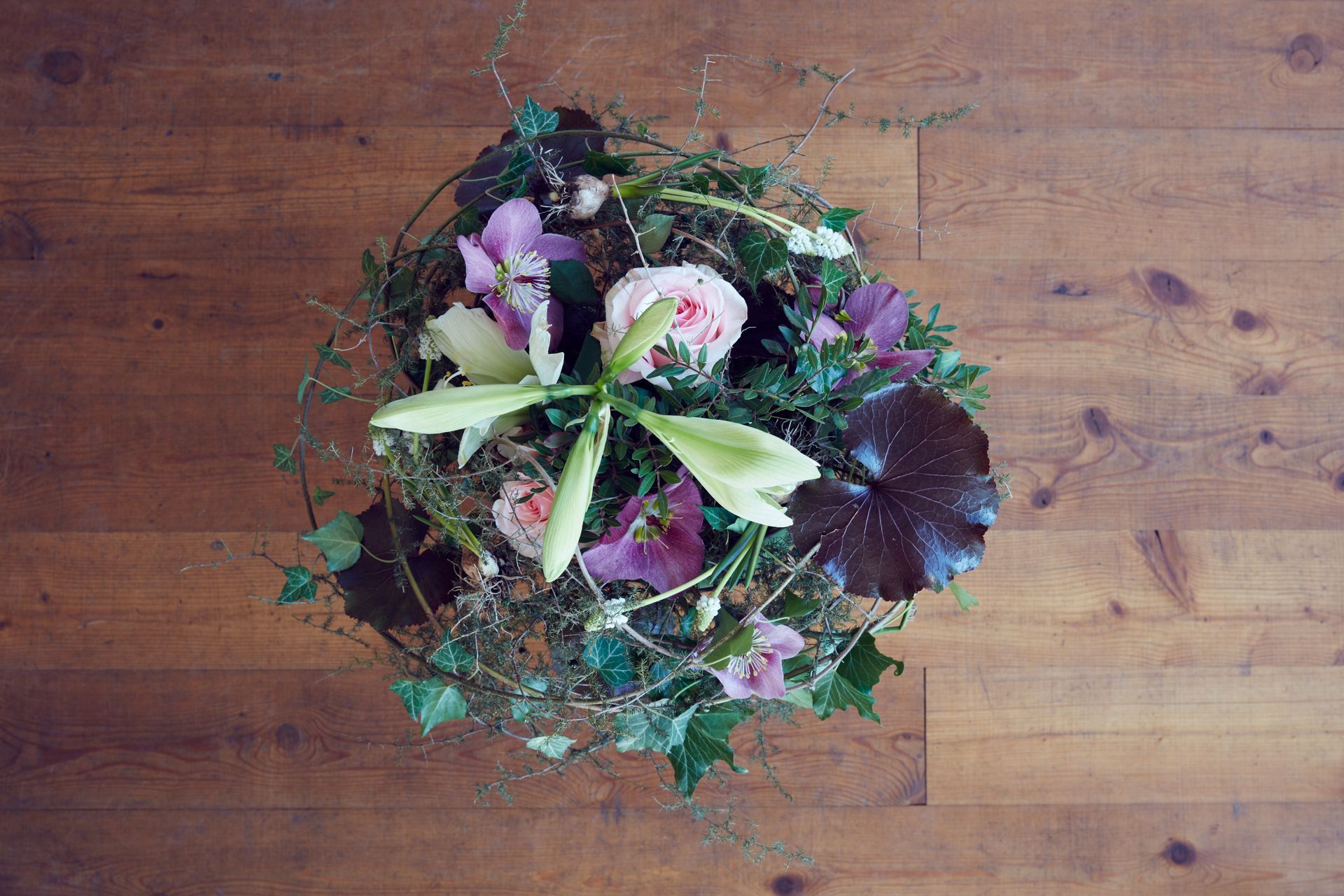 Dunkles Blumengesteck mit Efeu, Rosen und Lilien