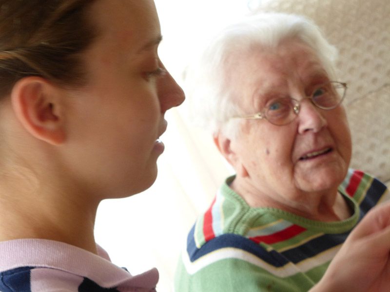 Eine Frau spricht mit einer älteren Frau, die eine Brille trägt