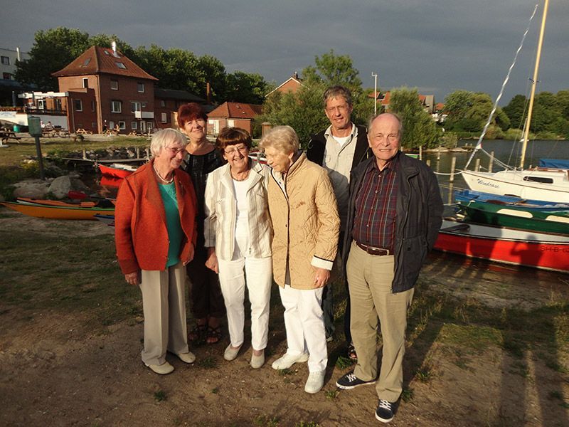 Eine Gruppe von Menschen posiert für ein Foto vor Booten