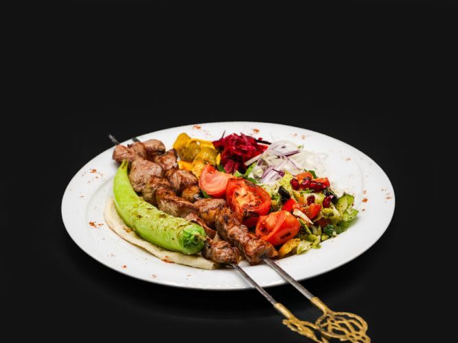 Ein Teller mit Fleischspiessen und Gemüse. Foto von Mama's Grillhaus.