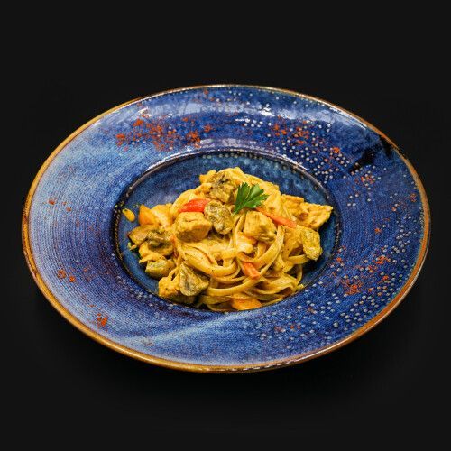 Ein blauer Teller mit Nudeln und Gemüse. Foto von Mama's Grillhaus.