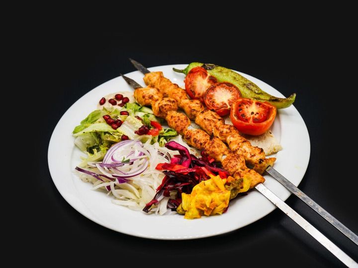 Eine Schüssel Salat mit Kopfsalat, Tomaten, Rotkohl und einer Gabel auf einem Holztisch.