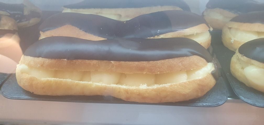 Éclairs de chocolate expuestos en una vitrina.