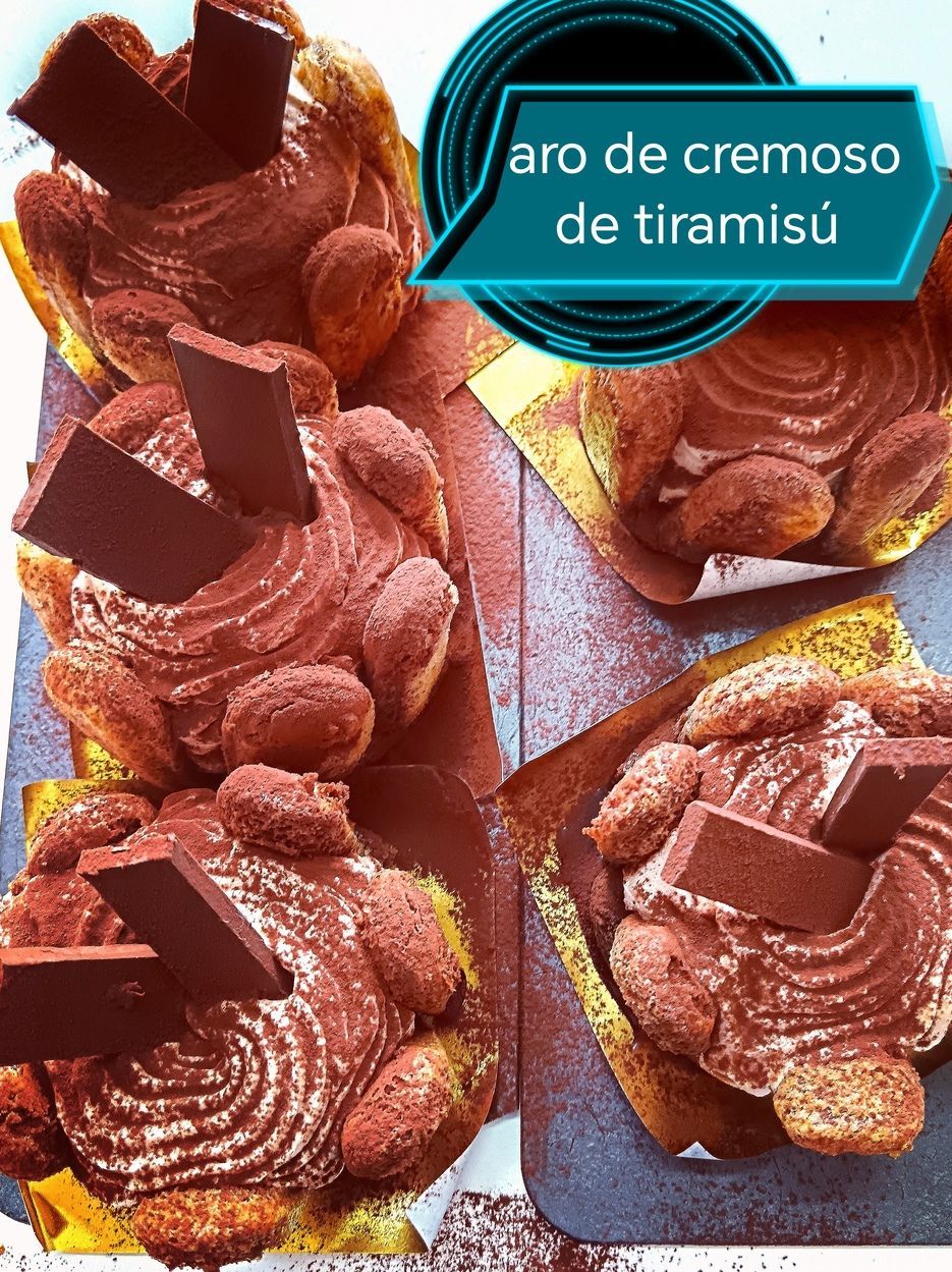 Cuatro postres individuales de tiramisú espolvoreados con cacao en polvo y cubiertos con trozos de chocolate.