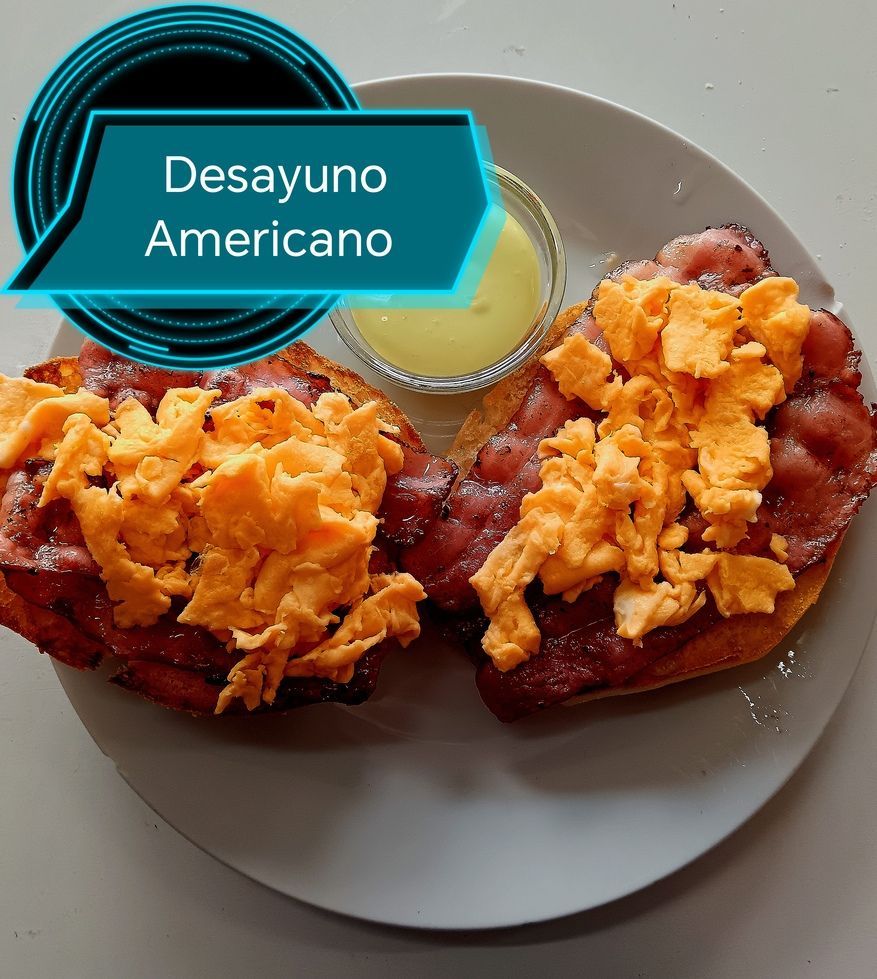 Desayuno americano: tostadas con tocino y huevos revueltos, más salsa.