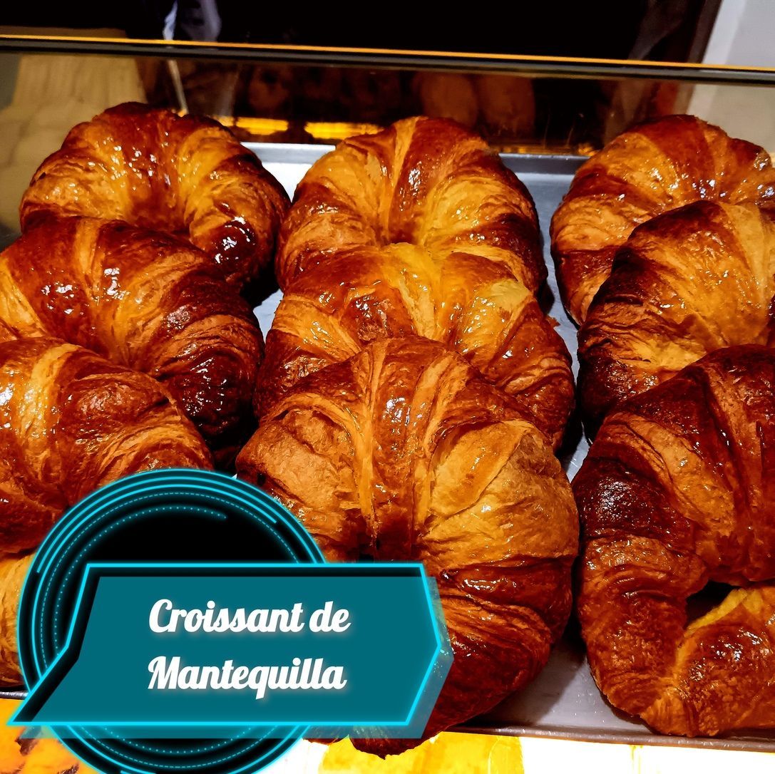 Croissants de mantequilla en exposición, brillantes y de color dorado, con etiqueta