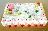 Pastel decorado con glaseado blanco, flores rosas y una bolsita de té.