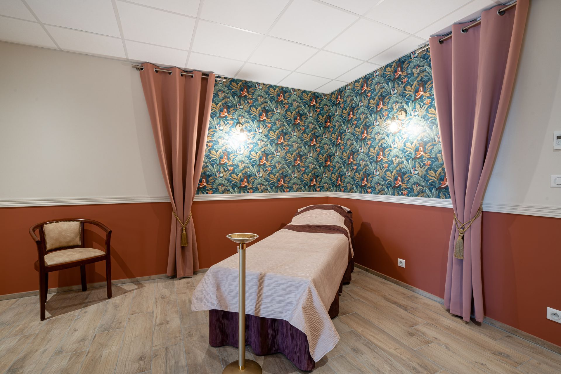 Une chambre funéraire avec un lit, une chaise et un bénitier.