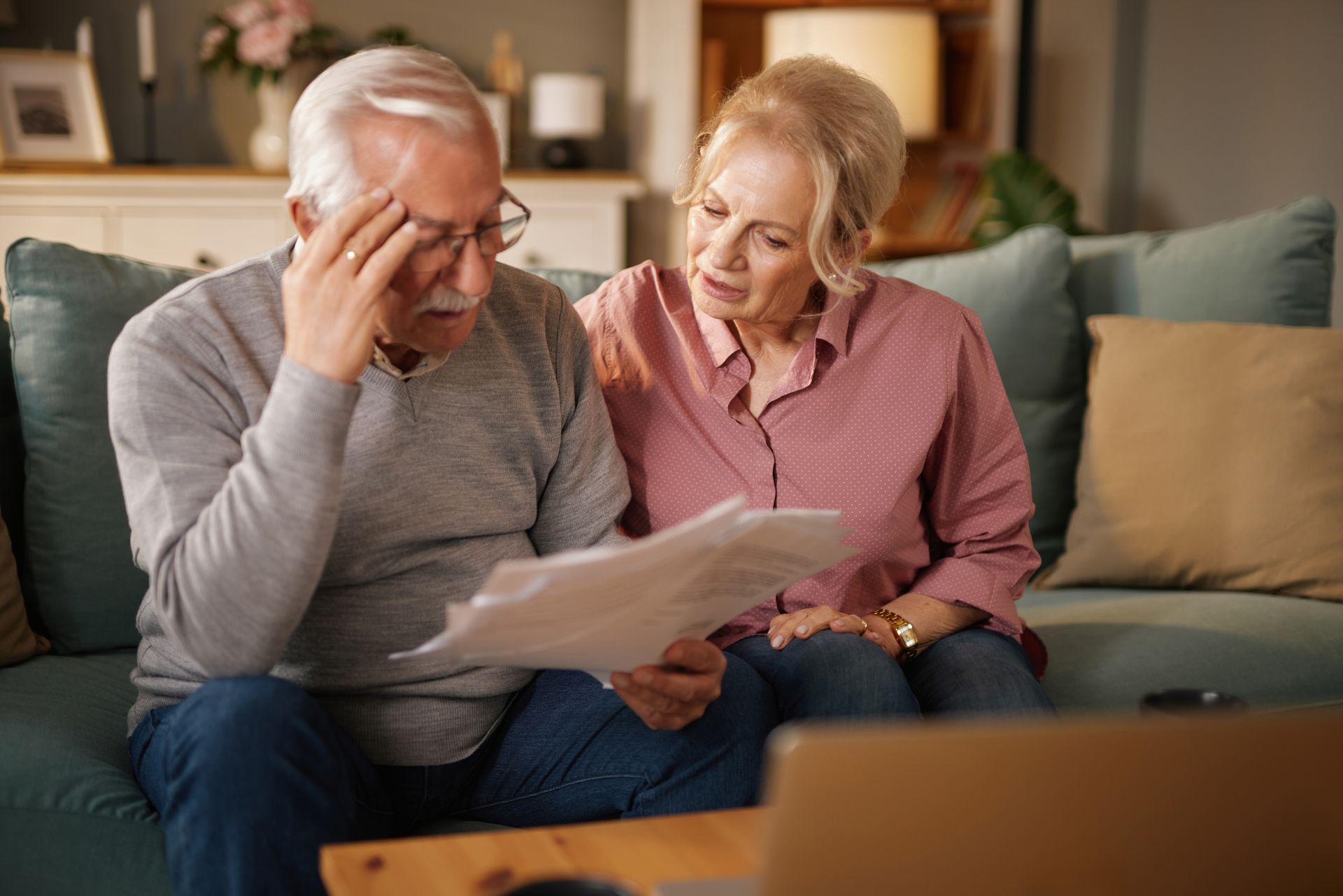 Un couple âgé, assis sur un canapé, examine un contrat de prévoyance.