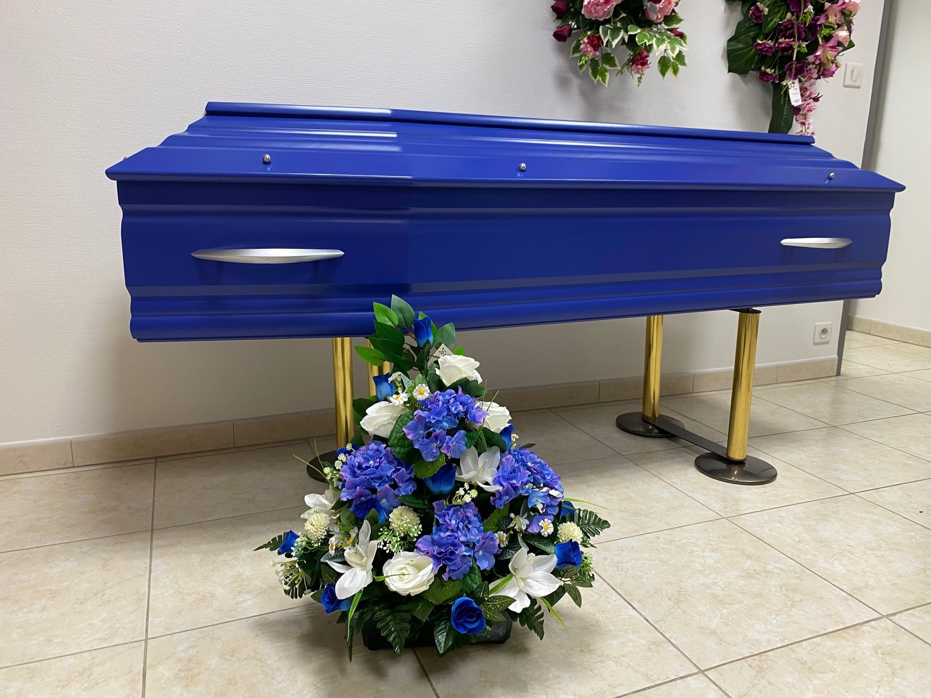 Un cercueil bleu avec une composition florale.