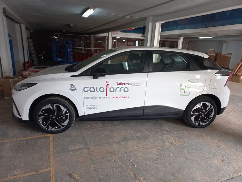Un coche blanco con la palabra Calaforra en el lateral está aparcado en un garaje.