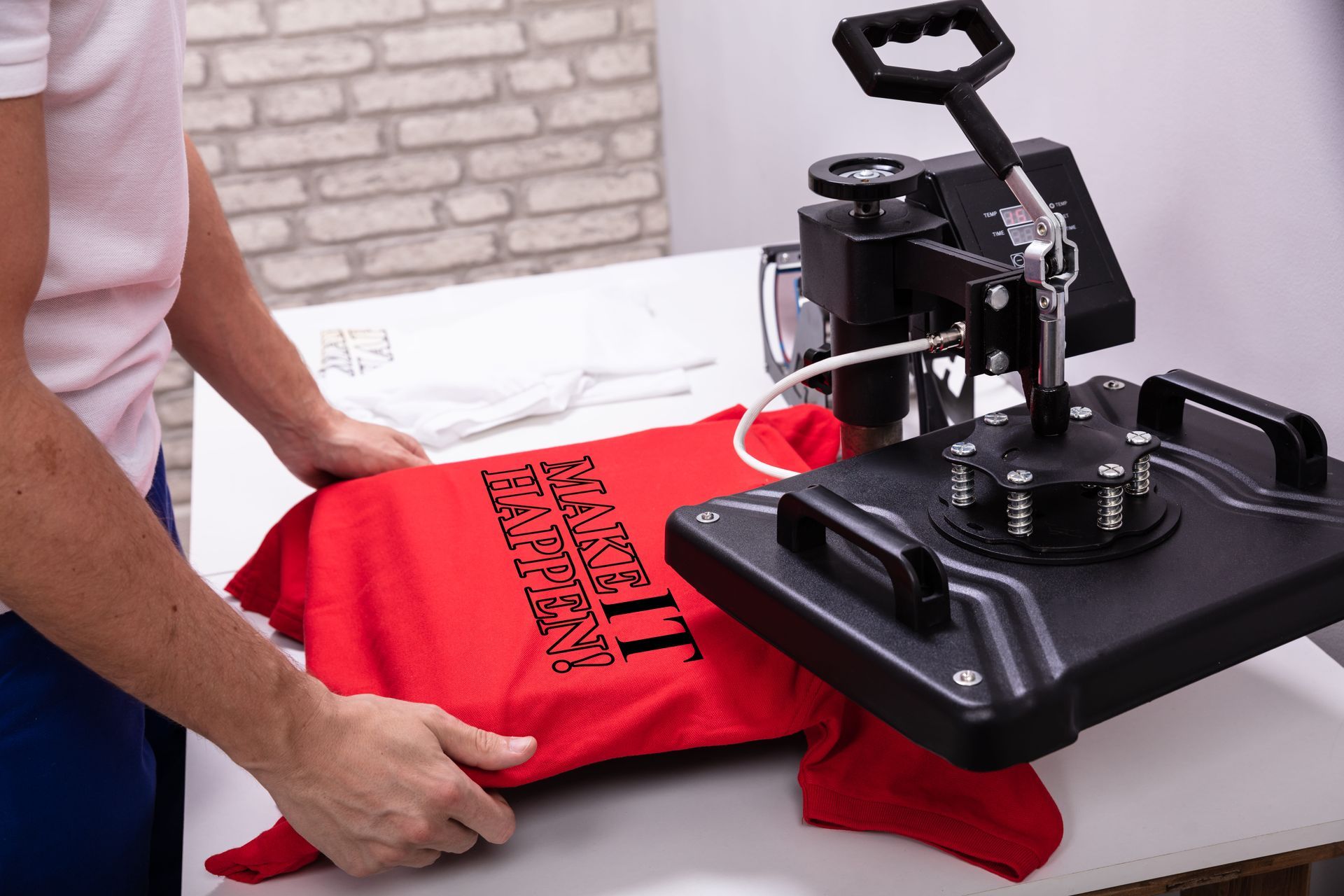 Una persona está prensando una camiseta roja en una máquina.