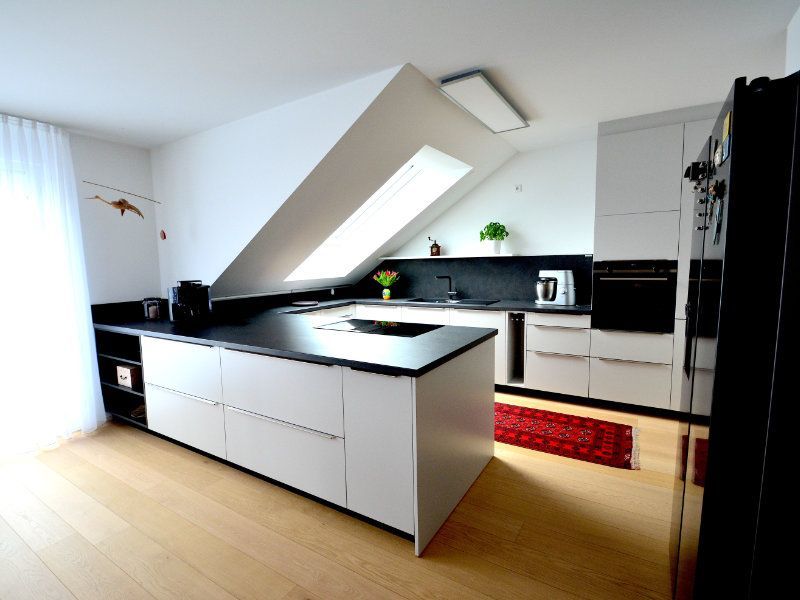 eine Küche mit weißen Schränken und schwarzen Arbeitsplatten