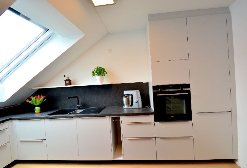 eine Küche mit weißen Schränken und einem schwarzen Ofen