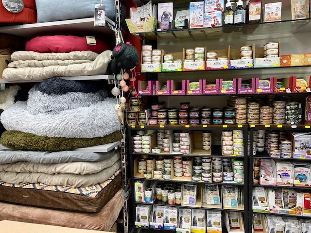 Des rayons remplis de paniers pour animaux et de conserves dans une animalerie.
