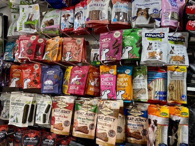 Présentation en rayon de différents emballages de friandises pour chiens dans un magasin.