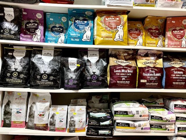 Des rayons remplis de sacs de nourriture pour chats de différentes marques dans une animalerie.