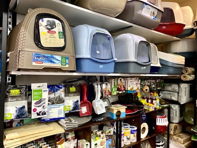 Des rayons remplis de bacs à litière pour chats et d'accessoires pour animaux de compagnie dans un magasin.