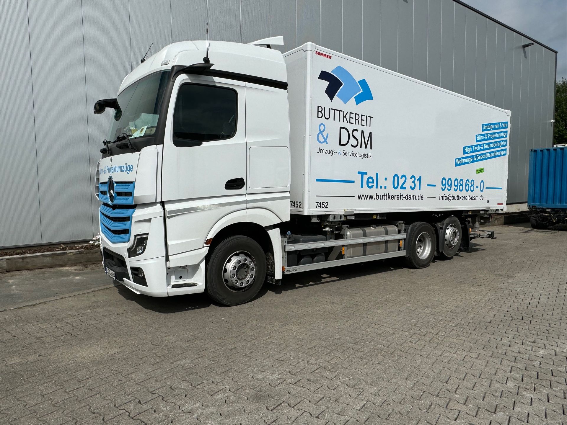 Ein weißer Sattelzug mit dem Logo „NUTRIFORM & DSM“ parkt in der Nähe eines Gebäudes.